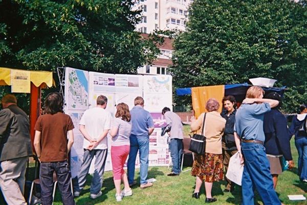 Group of residents looking at development plans in an outdoor exhibition. Residents look at different maps and discuss their content.