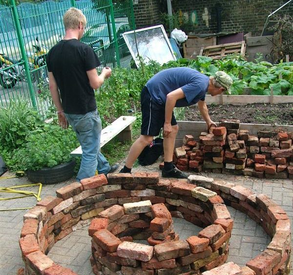 Two volunteers helping to build a planter for a community garden, built out of brick.